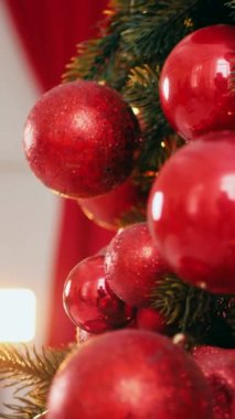 Dikey. Geleneksel Noel ağacı kırmızı süslemelerle süslenmiş. Güzel dekore edilmiş Noel ağacı olan şenlik odası. Kırmızı takılar bir tatil ağacına renk katıyor. Samimi ayarlar