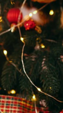 Dikey. Geleneksel Noel ağacı kırmızı süslemelerle süslenmiş. Güzel dekore edilmiş Noel ağacı olan şenlik odası. Kırmızı takılar bir tatil ağacına renk katıyor. Samimi ayarlar