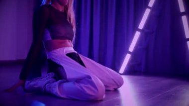 Baştan çıkarıcı dans eden seksi kadın. Titreyen bir dansçı, canlı mor ve mavi ışıkla yıkanmış, canlı neon bir üçgenin altında sahnenin enerjisini somutlaştırıyor. Bir sanatçının kadın vücudu, twerk ve yüksek topuklu ayakkabı sanatının bir kanıtı.