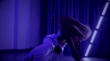 Baştan çıkarıcı dans eden seksi kadın. Titreyen bir dansçı, canlı mor ve mavi ışıkla yıkanmış, canlı neon bir üçgenin altında sahnenin enerjisini somutlaştırıyor. Bir sanatçının kadın vücudu, twerk ve yüksek topuklu ayakkabı sanatının bir kanıtı.