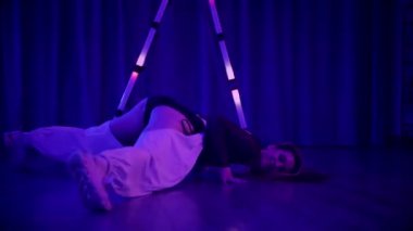 Baştan çıkarıcı dans eden seksi kadın. Titreyen bir dansçı, canlı mor ve mavi ışıkla yıkanmış, canlı neon bir üçgenin altında sahnenin enerjisini somutlaştırıyor. Bir sanatçının kadın vücudu, twerk ve yüksek topuklu ayakkabı sanatının bir kanıtı.