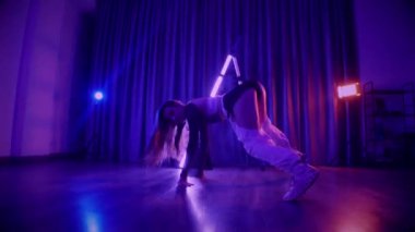 Baştan çıkarıcı dans eden seksi kadın. Titreyen bir dansçı, canlı mor ve mavi ışıkla yıkanmış, canlı neon bir üçgenin altında sahnenin enerjisini somutlaştırıyor. Bir sanatçının kadın vücudu, twerk ve yüksek topuklu ayakkabı sanatının bir kanıtı.