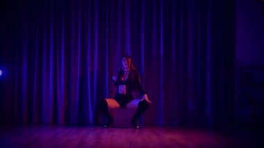 Baştan çıkarıcı dans eden seksi kadın. Yüksek topuklu bir dansçı, canlı renklerle yıkanmış, sahnenin heyecan verici enerjisini somutlaştırıyor. Akışkan hareketler, yüksek topuklar ve büyüleyici bir göz alıcı performans loş alanı ateşler. Sahnede Geceçöküşü