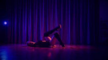 Baştan çıkarıcı dans eden seksi kadın. Yüksek topuklu bir dansçı, canlı renklerle yıkanmış, sahnenin heyecan verici enerjisini somutlaştırıyor. Akışkan hareketler, yüksek topuklar ve büyüleyici bir göz alıcı performans loş alanı ateşler. Sahnede Geceçöküşü