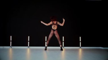 A dancer girl with a big ass in a thong dances erotically in hall. A captivating twerk, showcasing powerful movement and rhythm. Sexy woman dancing a seductive dance. Twerking, high heels, striptease.Energy and passion radiate from the performer's 