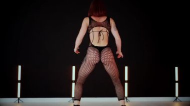 A dancer girl with a big ass in a thong dances erotically in hall. A captivating twerk, showcasing powerful movement and rhythm. Sexy woman dancing a seductive dance. Twerking, high heels, striptease.Energy and passion radiate from the performer's 