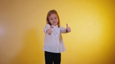 Genç iş kızı başparmak sallıyor, neşeyle gülüyor ve dans ediyor. Gözlüklü, güneş gözlüğü takan mutlu bir çocuk. Gülümseyen kız başparmağını kaldırıyor. Olumlu jestli kadın.