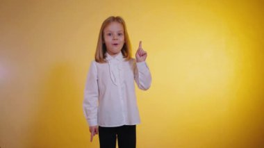 Genç bir kız, bir fikirle geniş gözlü, yukarı bakan, hardal sarısı bir arka fonun ılık parıltısıyla yıkanan. Parlak sarı fon, beyaz gömlekli küçük bir kız, düşünceli bir yüz ifadesi, yukarı işaret eden bir parmak. Beyaz gömlekli çocuk., 