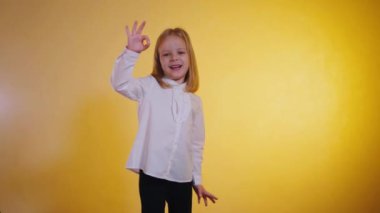 Kendine güveni olan genç bir kız canlı sarı bir arkaplan karşısında 