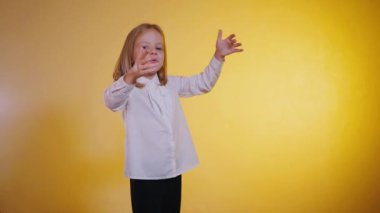 Küçük bir kız avuçlarıyla hava öpücüğü veriyor. Tatlı, sessiz bir hava öpücüğü, günışığının parıltısıyla yakalanmış. Eller dudaklara, sessiz bir selamlama. Gıcır gıcır beyaz gömlekli küçük bir kız, gizli bir öpücük teklif ediyor. Altın ışık hava öpücüğünü aydınlatır.