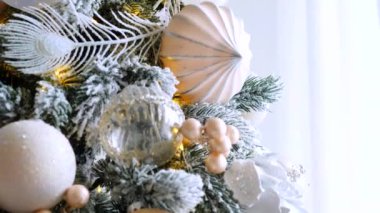 Narin bir kar yağışı ile süslenmiş Noel ağacı dalları. Zarif süsler sergiliyor. Güzel dekore edilmiş bir Noel ağacının yakın çekimi. Zarif süsler ve yanıp sönen ışıklar sergileniyor. Narin, karlı süsler, yavaşça parıldıyor. 