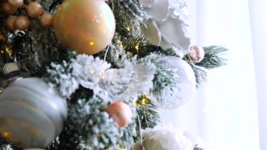 Narin bir kar yağışı ile süslenmiş Noel ağacı dalları. Zarif süsler sergiliyor. Güzel dekore edilmiş bir Noel ağacının yakın çekimi. Zarif süsler ve yanıp sönen ışıklar sergileniyor. Narin, karlı süsler, yavaşça parıldıyor. 