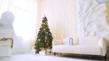 Noel ışıklarının parıltısı, görkemli bir ağaç ve sıcak bir şömineyle tamamlanmış sofistike bir oturma odasını aydınlatır. Modern bir evde, bir Noel ağacı, bir şömine ve yumuşak, davetkar bir atmosfere sahip bir kış harikalar diyarı.