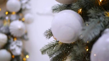 Narin bir kar yağışı ile süslenmiş Noel ağacı dalları. Zarif süsler sergiliyor. Güzel dekore edilmiş bir Noel ağacının yakın çekimi. Zarif süsler ve yanıp sönen ışıklar sergileniyor. Narin, karlı süsler, yavaşça parıldıyor. 
