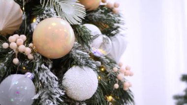 Narin bir kar yağışı ile süslenmiş Noel ağacı dalları. Zarif süsler sergiliyor. Güzel dekore edilmiş bir Noel ağacının yakın çekimi. Zarif süsler ve yanıp sönen ışıklar sergileniyor. Narin, karlı süsler, yavaşça parıldıyor. 