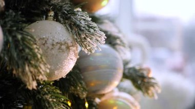 Narin bir kar yağışı ile süslenmiş Noel ağacı dalları. Zarif süsler sergiliyor. Güzel dekore edilmiş bir Noel ağacının yakın çekimi. Zarif süsler ve yanıp sönen ışıklar sergileniyor. Narin, karlı süsler, yavaşça parıldıyor. 