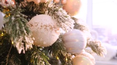 Narin bir kar yağışı ile süslenmiş Noel ağacı dalları. Zarif süsler sergiliyor. Güzel dekore edilmiş bir Noel ağacının yakın çekimi. Zarif süsler ve yanıp sönen ışıklar sergileniyor. Narin, karlı süsler, yavaşça parıldıyor. 