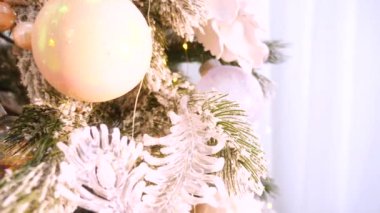 Narin bir kar yağışı ile süslenmiş Noel ağacı dalları. Zarif süsler sergiliyor. Güzel dekore edilmiş bir Noel ağacının yakın çekimi. Zarif süsler ve yanıp sönen ışıklar sergileniyor. Narin, karlı süsler, yavaşça parıldıyor. 