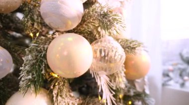 Narin bir kar yağışı ile süslenmiş Noel ağacı dalları. Zarif süsler sergiliyor. Güzel dekore edilmiş bir Noel ağacının yakın çekimi. Zarif süsler ve yanıp sönen ışıklar sergileniyor. Narin, karlı süsler, yavaşça parıldıyor. 