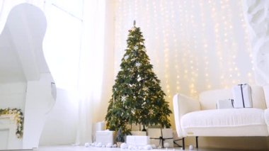 Noel ışıklarının parıltısı, görkemli bir ağaç ve sıcak bir şömineyle tamamlanmış sofistike bir oturma odasını aydınlatır. Modern bir evde, bir Noel ağacı, bir şömine ve yumuşak, davetkar bir atmosfere sahip bir kış harikalar diyarı.