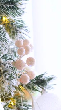 Dikey, Noel ağacı dalları, narin bir kar yağışı ile süslenmiş, zarif süsler sergiliyor. Süslü bir Noel ağacının yakın çekimi. Zarif süsler ve parıldayan ışıklar sergiliyor..