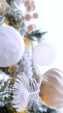 Dikey, Noel ağacı dalları, narin bir kar yağışı ile süslenmiş, zarif süsler sergiliyor. Süslü bir Noel ağacının yakın çekimi. Zarif süsler ve parıldayan ışıklar sergiliyor..