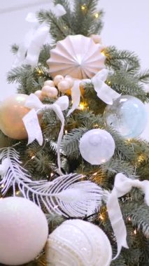 Dikey, Noel ağacı dalları, narin bir kar yağışı ile süslenmiş, zarif süsler sergiliyor. Süslü bir Noel ağacının yakın çekimi. Zarif süsler ve parıldayan ışıklar sergiliyor..
