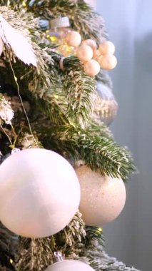 Dikey, Noel ağacı dalları, narin bir kar yağışı ile süslenmiş, zarif süsler sergiliyor. Süslü bir Noel ağacının yakın çekimi. Zarif süsler ve parıldayan ışıklar sergiliyor..