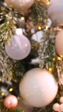 Dikey, Noel ağacı dalları, narin bir kar yağışı ile süslenmiş, zarif süsler sergiliyor. Süslü bir Noel ağacının yakın çekimi. Zarif süsler ve parıldayan ışıklar sergiliyor..