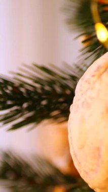 Dikey. Noel ağacı sıcak, altın ışıklarla süslenmiş, el yapımı süslemeler. Noel ağacı dalları, parlak ışıklar, ve el yapımı saman yıldızı, turuncu, sıcaklık ve atmosfer yaratıyor.