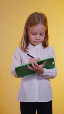 Dikey, gülümseyen bir kız ifadesi, yeşil bir tablette fikirler yakalıyor. Mutlu genç sanatçı, özenle yeşil bir tablet üzerinde yaratıyor. Dijital sanata kendini kaptırmış bir çocuk.