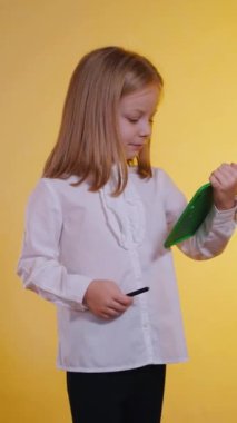 Dikey, gülümseyen bir kız ifadesi, yeşil bir tablette fikirler yakalıyor. Mutlu genç sanatçı, özenle yeşil bir tablet üzerinde yaratıyor. Dijital sanata kendini kaptırmış bir çocuk.