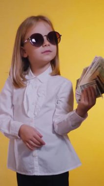 Dikey, kendinden emin gülümseyen bir çocuk para dolarlarını hayranı gibi elinde tutuyor. Beyaz gömlekli, ciddi, genç bir iş kızı, kendine güveniyor ve para sayıyor, satın almaya hazır. İş gibi.,