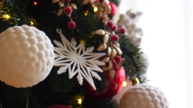 Narin bir kar yağışı ile süslenmiş Noel ağacı dalları. Zarif süsler sergiliyor. Güzel dekore edilmiş bir Noel ağacının yakın çekimi. Zarif süsler ve yanıp sönen ışıklar sergileniyor..