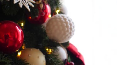 Narin bir kar yağışı ile süslenmiş Noel ağacı dalları. Zarif süsler sergiliyor. Güzel dekore edilmiş bir Noel ağacının yakın çekimi. Zarif süsler ve yanıp sönen ışıklar sergileniyor..