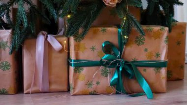 Işıldayan bir Noel ağacının altında bir sürü güzel hediye. Noel neşesi, güzel paketlenmiş hediyeler ve şenlikli ışıklardan gelen hafif bir parıltı..