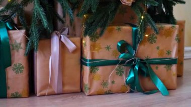 Işıldayan bir Noel ağacının altında bir sürü güzel hediye. Noel neşesi, güzel paketlenmiş hediyeler ve şenlikli ışıklardan gelen hafif bir parıltı..