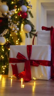 Masadaki Noel ağacının önündeki dikey, kırmızı hediye kutusu. Ağaç zeminli kırmızı hediye kutusu. Masanın üstünde Noel ağacı ve kırmızı hediye var. Şenlik ağacının yanında canlı kırmızı hediye kutusu.