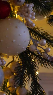 Dikey, Noel ağacı dalları, narin bir kar yağışı ile süslenmiş, zarif süsler sergiliyor. Güzel dekore edilmiş bir Noel ağacının yakın çekimi. Zarif süsler sergiliyor. 