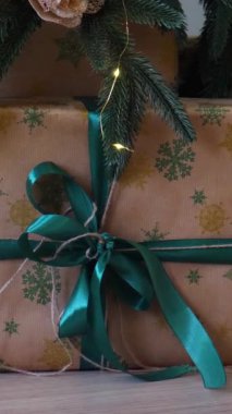 Dikey, parıldayan bir Noel ağacının altında bir sürü güzel yuva hediyeleri. Noel neşesi, güzel paketlenmiş hediyeler ve şenlikli ışıklardan gelen hafif bir parıltı..