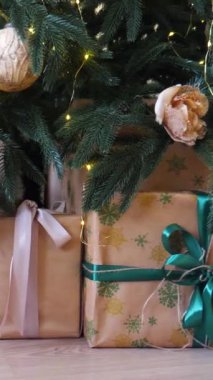 Dikey, parıldayan bir Noel ağacının altında bir sürü güzel yuva hediyeleri. Noel neşesi, güzel paketlenmiş hediyeler ve şenlikli ışıklardan gelen hafif bir parıltı..
