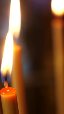 Dikey. Yanıp sönen alevler, loş alana sıcak bir ışık saçıyor. Dua mumlarının yumuşak parıltısı, karanlıkta bir fener. Mumlar parlak yanıyor, makro ateş ediliyor.