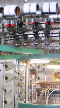 Dikey, arabalara kumaş dokuma. Fabrikadaki ipliklerden kumaş üretimi. Tekstil fabrikası endüstrisi. Kumaş yapma makineleri.