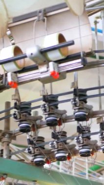 Dikey, arabalara kumaş dokuma. Fabrikadaki ipliklerden kumaş üretimi. Tekstil fabrikası endüstrisi. Kumaş yapma makineleri.