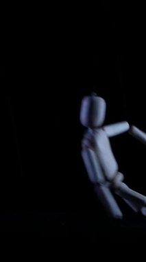 Dikey, tahta manken karanlıkta asılı duruyor. İpte asılı ürkünç ahşap figür. Siyah arka plana karşı ürkütücü manken silueti. Gölgelerde sallanan uğursuz tahta kukla