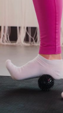 Dikey. Gülümseyen kadın esneme egzersizleri yapar. Yoga yaparken güneşli bir odada esneyen pembe elbiseli bir kadın. Esneklik eğitimi, fiziksel egzersizler.