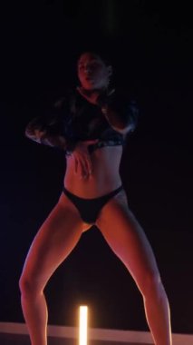 Vertical, Sexy woman dancing a seductive dance. A dancer girl with a big ass in a thong dances erotically in a dark hall. Twerk, high heels, striptease