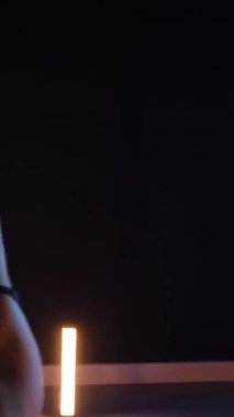 Vertical, Sexy woman dancing a seductive dance. A dancer girl with a big ass in a thong dances erotically in a dark hall. Twerk, high heels, striptease