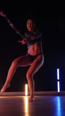 Vertical, Sexy woman dancing a seductive dance. A dancer girl with a big ass in a thong dances erotically in a dark hall. Twerk, high heels, striptease