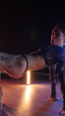Vertical, Sexy woman dancing a seductive dance. A dancer girl with a big ass in a thong dances erotically in a dark hall. Twerk, high heels, striptease